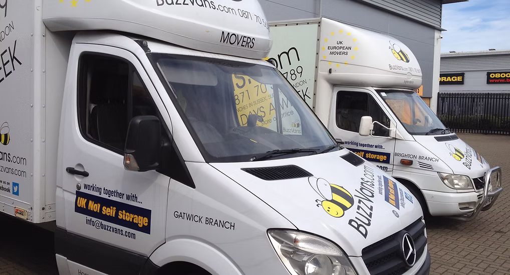 Five branded Buzz Movers vans outside a warehouse